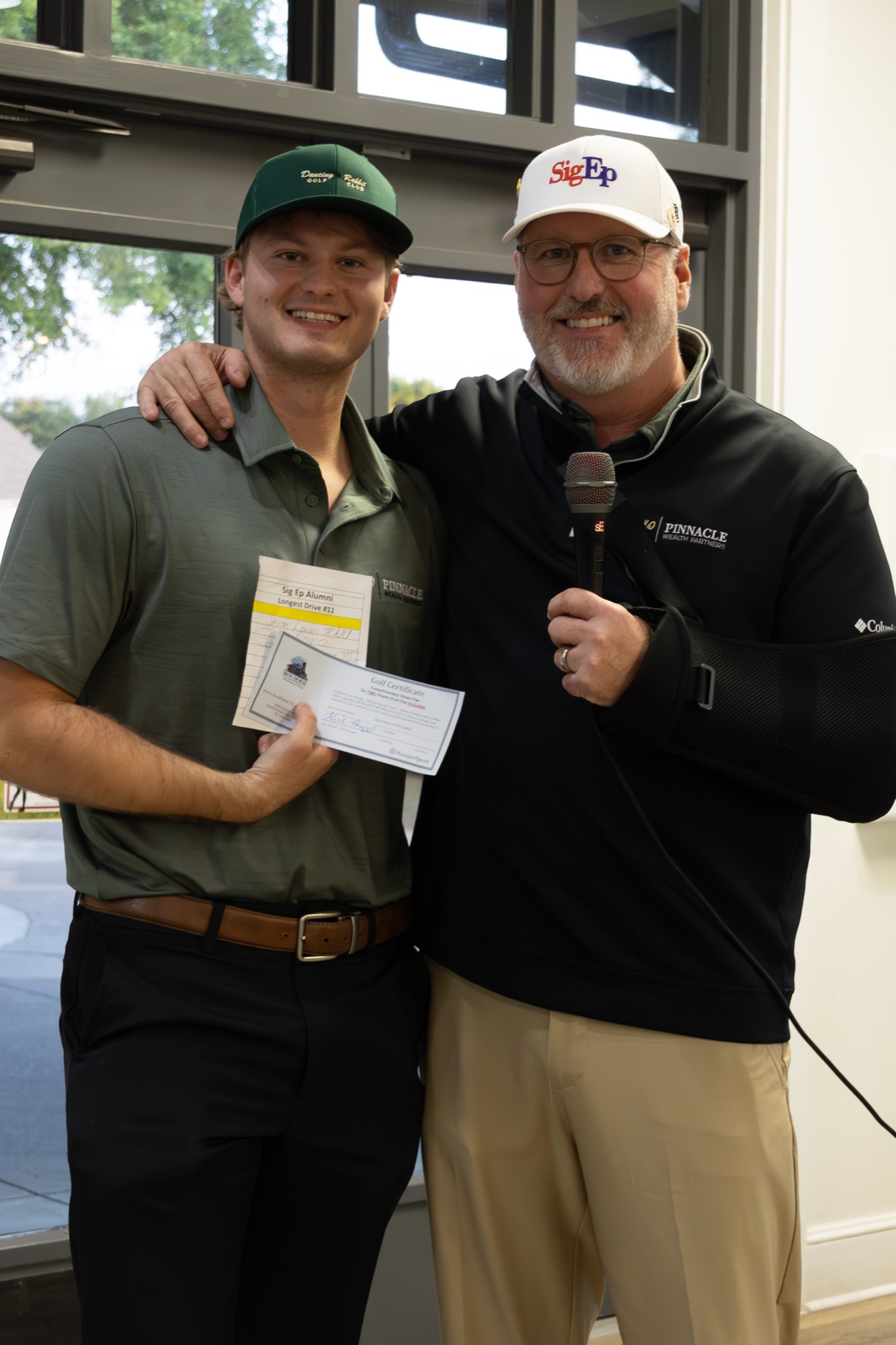 A Texas Kappa brother and a tournament host with the microphone, presenting at the golf tournament.