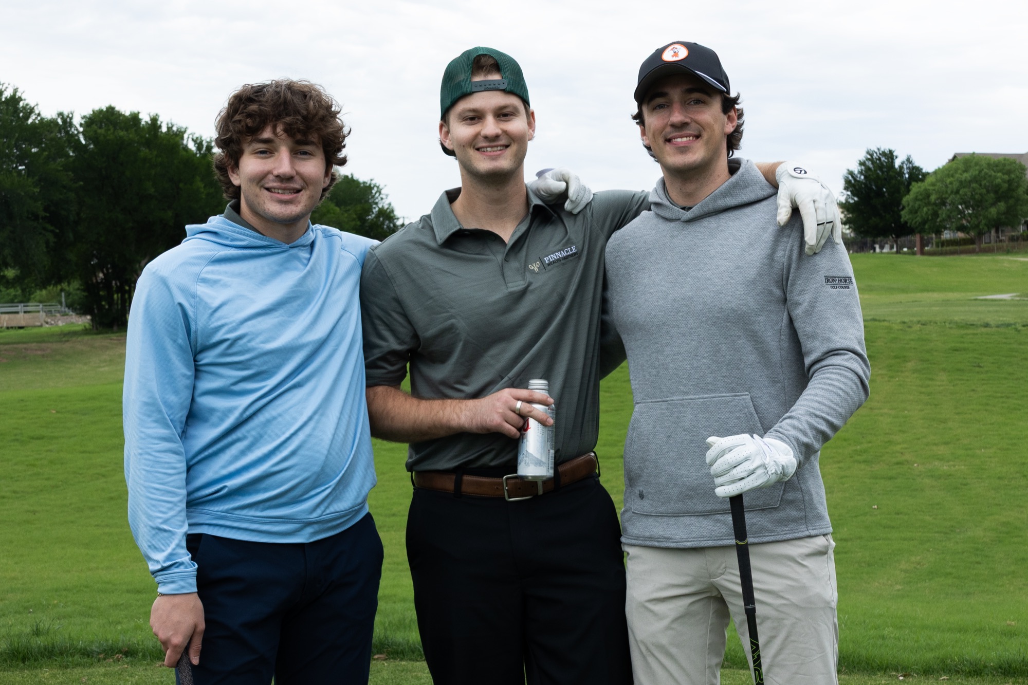 Three golfers posing together on the course at the SigEp golf tournament.