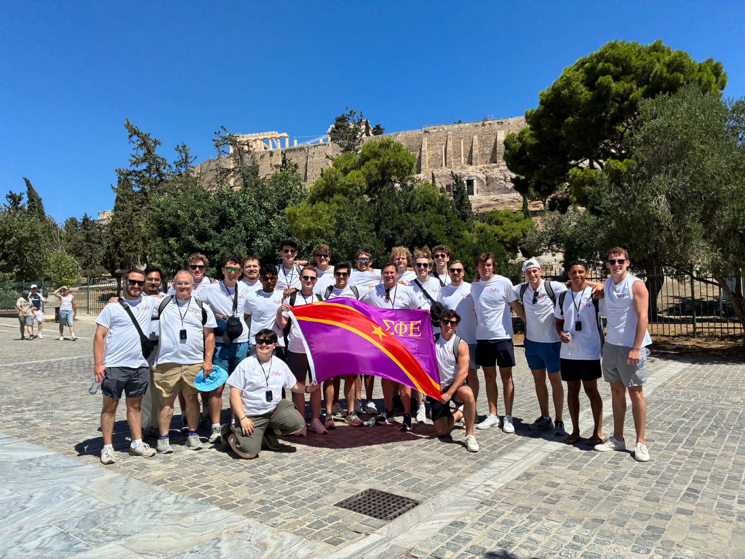Texas Kappa brothers posing with the Sigma Phi Epsilon chapter flag in front of the Acropolis in Athens, Greece.